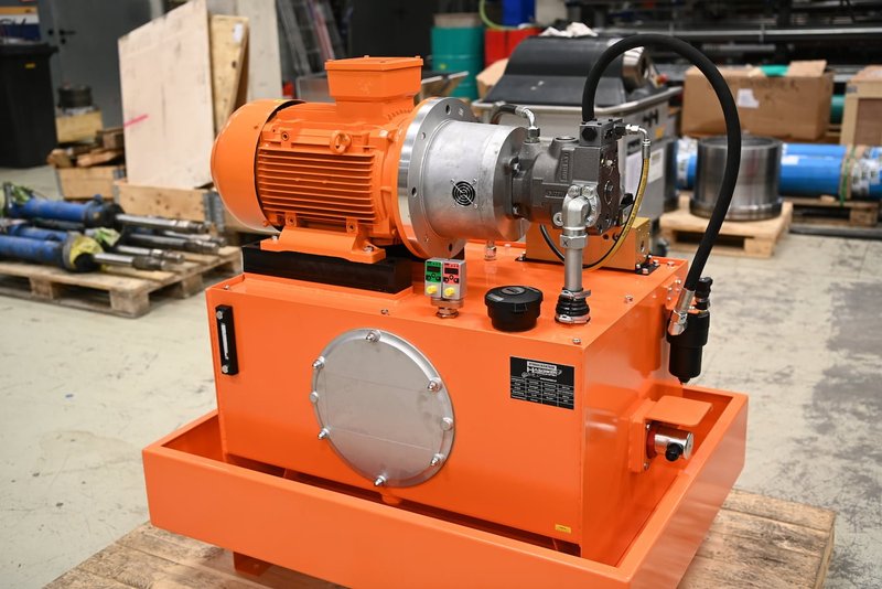 Hydraulikaggregat fertig montiert Orangefarbenes Hydraulikaggregat mit Elektromotor und Pumpe auf Palette in der Werkstatt